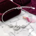 Elegáns ezüst karkötő egymásba fonódó karika medállal